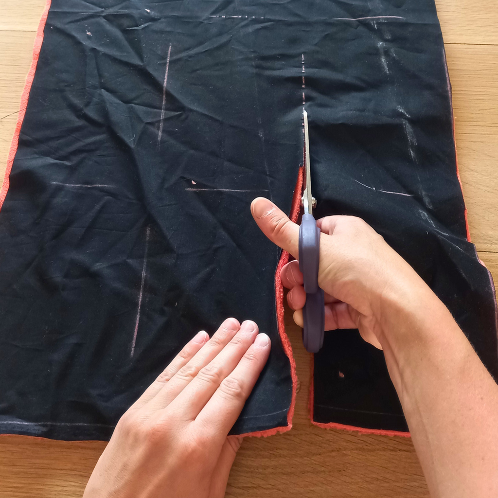 main découpant un tissu coton noir