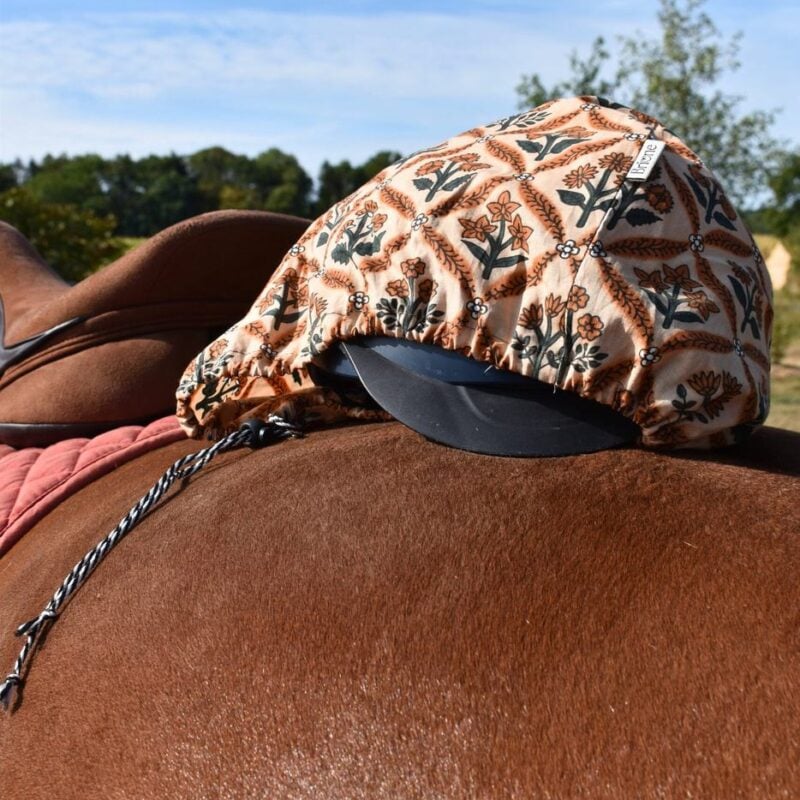 housse de bombe en coton léger marron; légèrement ouverte, posée sur la croupe d'un cheval bai